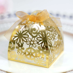 Elegant gold laser-cut hollow wedding favor box with floral patterns and a gold ribbon bow