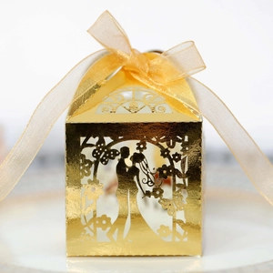 Elegant gold laser-cut wedding favor box with romantic couple silhouette and ribbon