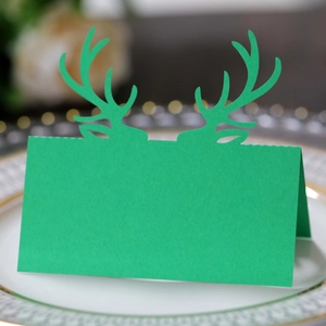 Segnaposto verde con corna di renna su piatto per decorazione della tavola di Natale