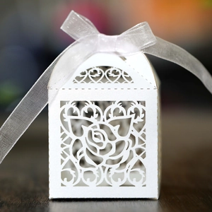 Detail of white laser-cut rose hollow favor box with elegant cream ribbon bow
