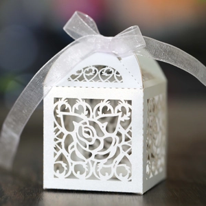 Macro detail of laser-cut rose and heart patterns on pearlescent white candy box with ribbon