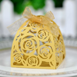 Elegante gouden lasergesneden rozen snoepdoos met lintstrik op een wit bord