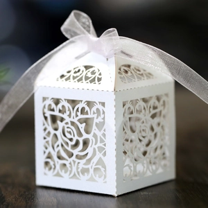 Detailed close-up of a white laser-cut wedding favor box with elegant rose patterns and ribbon