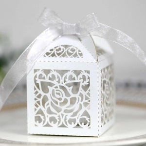 Detail of laser-cut white wedding candy box with rose patterns and silver organza ribbon