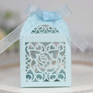 Detail of light blue laser-cut wedding candy box with rose pattern and silk ribbon bow