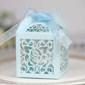 Detail of light blue laser-cut wedding favor box with rose pattern and silk ribbon bow