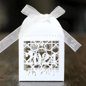 Macro detail of white laser-cut graduation candy box with 2021 class motif and bow