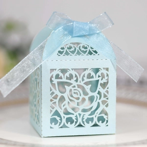 Detail of light blue laser-cut candy box with rose patterns and organza ribbon