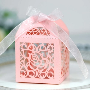 Detailed laser-cut rose patterns on a pink pearlescent wedding candy box with ribbon
