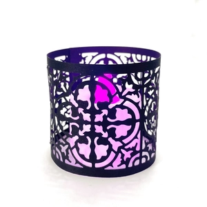 Black laser-cut candle holder sleeve with geometric floral patterns and purple LED glow