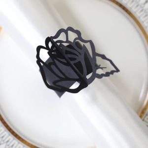 Elegante servilletero de papel negro cortado con láser con diseño de rosa sobre un plato