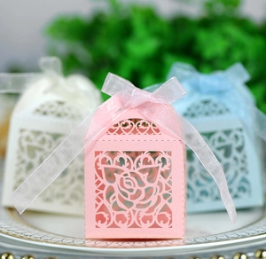 Detailed laser-cut rose and heart patterns on wedding favor boxes with organza ribbons