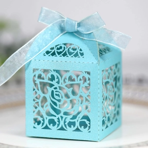 Detail of light blue laser-cut favor box featuring elegant rose patterns and satin ribbon bow