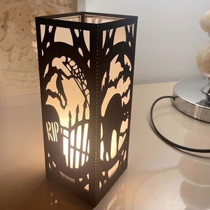 Black laser-cut Halloween candle holder with cemetery silhouette and warm LED light