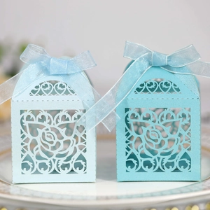 Detail of laser-cut rose hollow favor boxes in sky blue with elegant silk ribbon bows