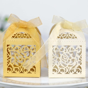 Close-up of laser-cut rose patterns on gold and cream wedding favors with silk ribbons
