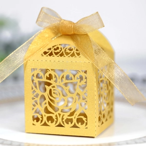Detailed laser-cut rose pattern on gold candy box with a silk ribbon bow