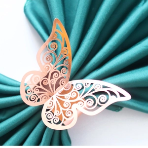 Elegant laser-cut hollow butterfly napkin ring in rose gold on a dark green silk background