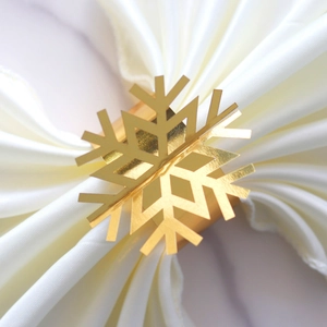 Elegant gold snowflake napkin ring with mirrored finish on a white silk table napkin