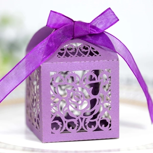 Detail of purple laser-cut wedding favor box with rose patterns and a silk ribbon bow