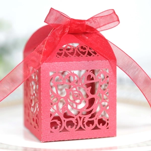 Macro shot of laser-cut rose and heart patterns on red cardstock with a red organza bow