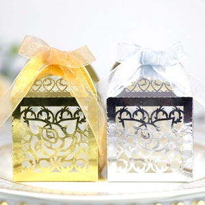 Detail of laser-cut rose pattern gift boxes in gold and silver with organza ribbons