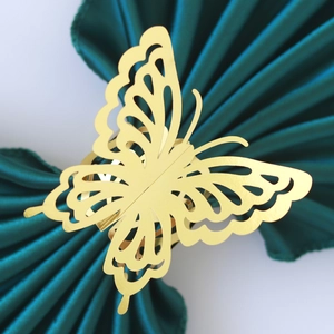 Detailed view of golden laser-cut butterfly napkin ring on green satin fabric