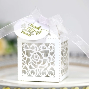 Close-up of laser-cut rose patterns on white candy box with Thank You tag and ribbon