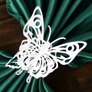 Rond de serviette papillon blanc découpé au laser sur un tissu en satin vert foncé chic