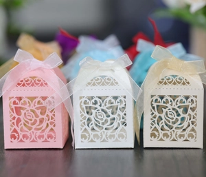 Detail of laser-cut rose patterns on wedding favor boxes with organza ribbon bows