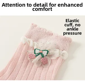 Détail de chaussettes roses pour filles avec dentelle, bord élastique et broderie cerise