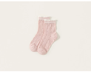 Détail de chaussettes roses en maille pour filles avec motifs cœurs et volants blancs
