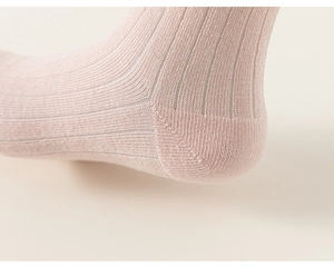 Détail de chaussettes en maille rose montrant la texture côtelée et la couture du talon