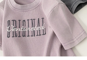 Détail d'un t-shirt en coton violet avec broderie blanche et imprimé original