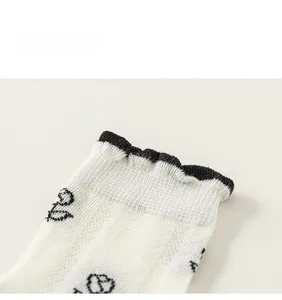 Détails de chaussettes en coton blanc avec bords ondulés noirs et motifs de cœurs
