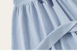 Detail von blau kariertem Mädchenkleid mit dunkelblauer Schleife und Bindegürtel