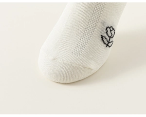 Gros plan de chaussettes blanches en maille pour enfants avec motif de rose noire et coton