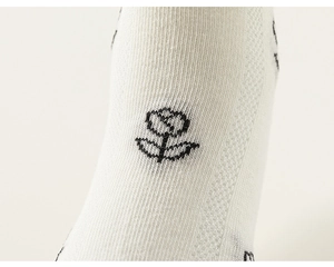 Gros plan sur un tricot blanc avec un motif de rose noire brodé de style minimaliste