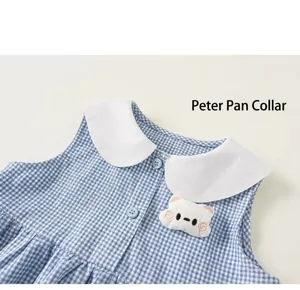 Detail eines karierten Babykleids mit weißem Peter-Pan-Kragen und Bären-Applikation
