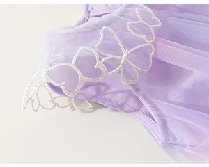 Détail d'une robe en tulle violette montrant de délicates broderies de papillons blancs