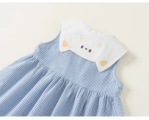 Detailaufnahme des blau karierten Mädchenkleides mit Katzenmotiv auf dem weißen Kragen