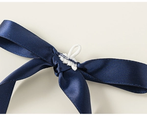 Detailaufnahme einer dunkelblauen Satin-Schleife mit glänzender Textur und Gummiband
