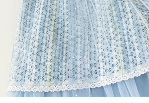 Détail de la robe en tulle bleu clair avec sequins étoilés et ourlet en dentelle crochetée