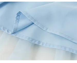Détail du tissu bleu clair et du mesh blanc avec un ourlet soigné sur une robe de fille
