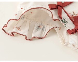 Dettaglio vestito neonata con stampa bacche, fiocco rosso e bordo arricciato