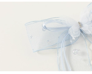 Détail d'une pince à cheveux papillon en tulle bleu clair avec strass et perles