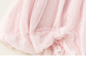 Dettaglio di tulle a rete con paillettes rosa tenue e pieghe a strati per abito da bambina