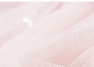 Dettaglio del tessuto in tulle rosa a rete con delicati motivi floreali di paillettes
