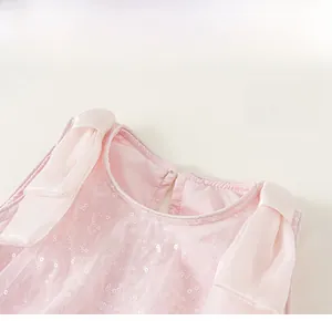 Dettaglio di un vestito rosa da bambina con paillettes luccicanti e fiocchi sulle spalle