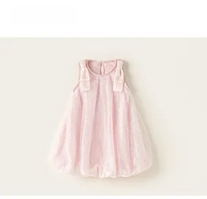 Dettaglio di un abito in mesh con paillettes rosa con fiocchi e orlo a bolle leggero